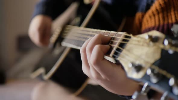 DOF Closeup A Teenager Boy Plays a Black Acoustic Guitar