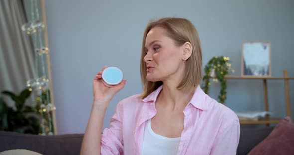 Young Beatiful Woman Speaking While Presenting Beauty Cosmetics To Camera. Smiling Female Vloger alt