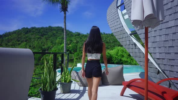 Back View Pretty Girl Walking Towards An Infinity Pool In Luxurious Villa