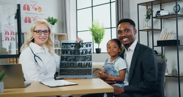 Man and His Cute Small Daughter which Posing on Camera Together with Female Doctor alt
