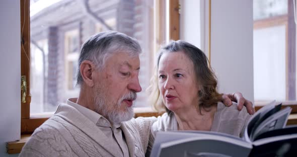 Portrait of Elderly Men and Wives Sitting with a Book and Discussing Its Contents in Their Cozy alt