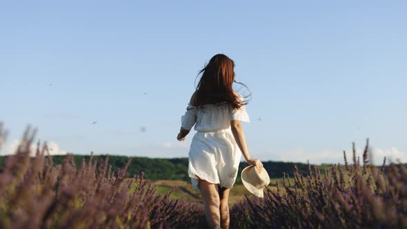 Happy Young Woman in a White Dress Running Through Lavender Field
