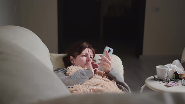 Woman Is Ill at Home Lies on the Couch and Uses the Phone