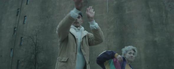 Young Couple Dancing Vogue to Camera against Old Concrete Building alt