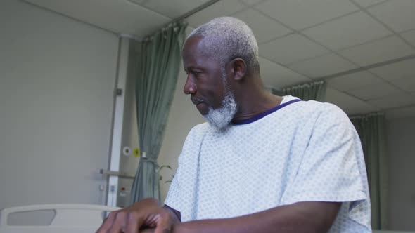 African american male patient looking at window holding cane in hospital room alt