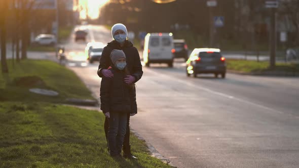 Mother Adjusts Her Daughter's Medical Mask on the Street of a European City .