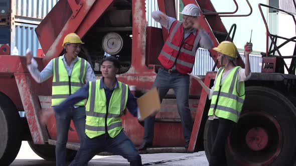 Funny workers and engineer dance at cargo containers. Young dock worker team dancing in a shipyard