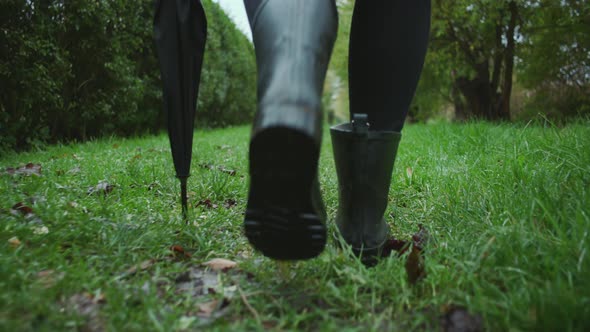 Woman In Boots Walking Through Wet Grass