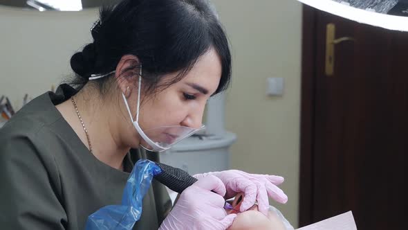 Cosmetologist Applies Permanent Pigment Tattoo to Female Lips with Tattoo Needle in Salon