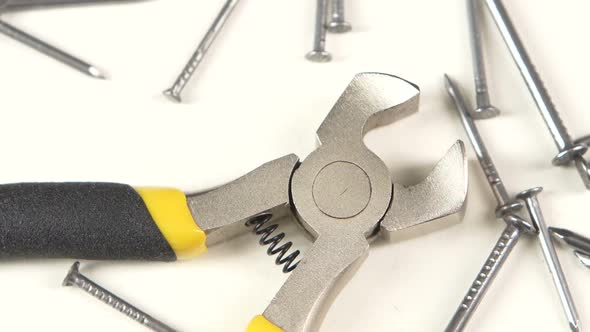 Wire Cutters with Yellow, Gray Handle on White Among Nails, Rotation, Close Up alt