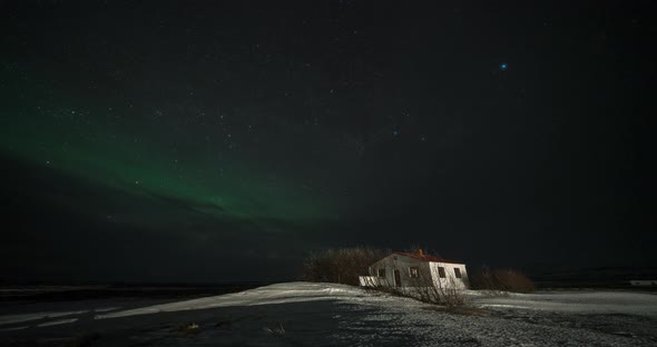 Timelapse of Aurora Borealis Northern Lights Over Small Building in the Show Field, Iceland