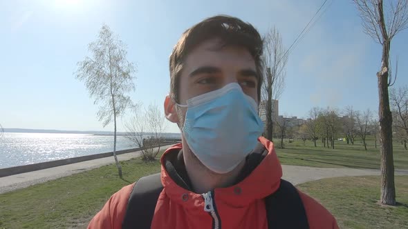 A Young Man in a Medical Mask Walks Along the City's Empty Embankment at Quarantine. Selfie Shot