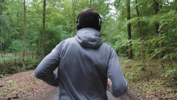 Man Running Through Forest Wearing Headphones