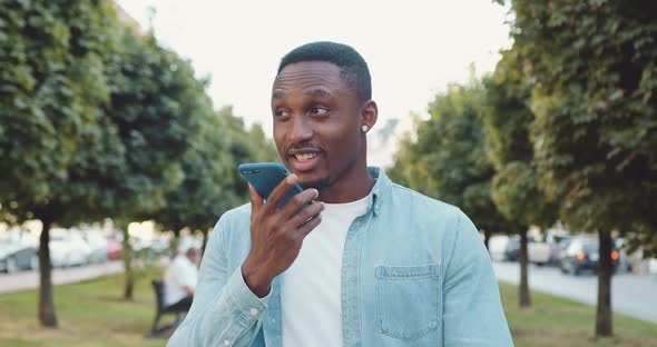 Black-Skinned Man in Casual Clothes Has Video Call while Walking Alone in the Urban Alley  alt
