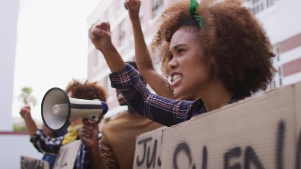 Diverse group of men and women holding placards shouting using megaphone during protest alt