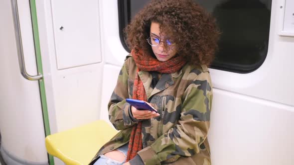 Slow motion young multiethnic women travelling underground using smart phone alt