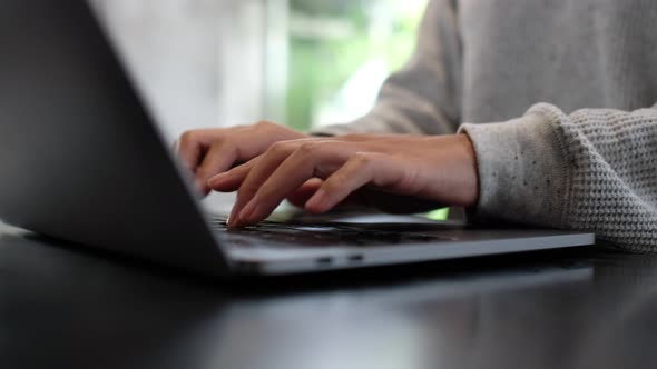 a woman working and typing on laptop computer keyboard on the table