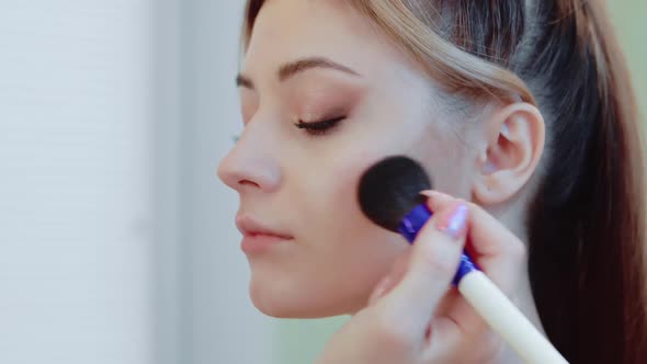 Closeup of a Beautiful Young Woman Applying a Powder Brush