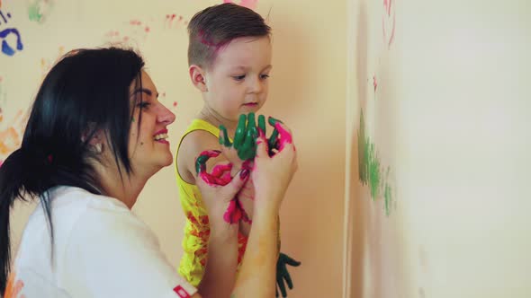 Happy Mother and Her Cute Boy Having Fun Together Leaving Their Colorful Handprints and Painting on alt