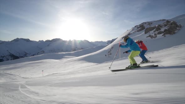 A man and woman couple skiing together in the snow at a ski resort alt