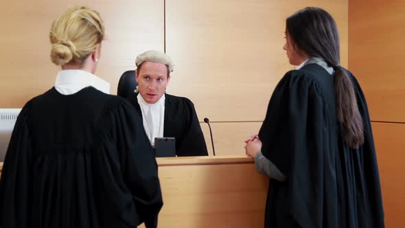 Two Lawyers Standing and Speaking with the Judge alt