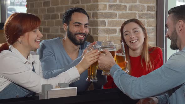 Cheerful Friends Clinking Beer Glasses at the Pub