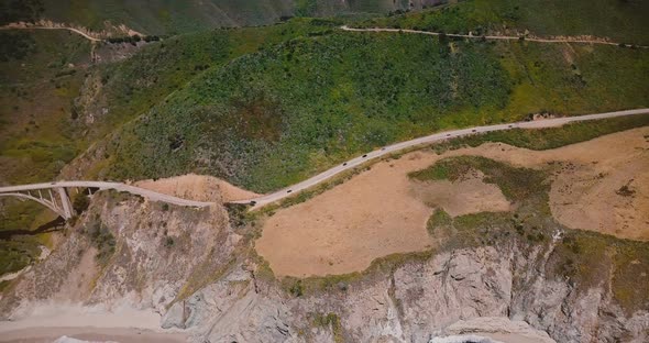 Top View Drone Panning Left To Reveal Cars on Amazing Highway 1 and Bixby Canyon Bridge Sunny alt