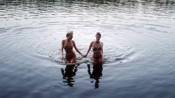 Two Women Swimsuit Bikini Come Out of Lake Laughing and Splashing Water