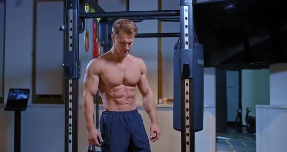 Tired Athlete Stands at the Horizontal Bar and Sighs Rest After Exercise alt