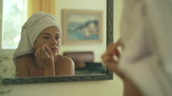 Caucasian Woman Doing Eye Makeup in Front of the Mirror alt