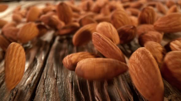 Super Slow Motion Detail Shot of Almonds Rolling Towards on Wooden Background at 1000Fps alt