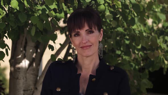 Woman with big earrings with small smile glancing up alt