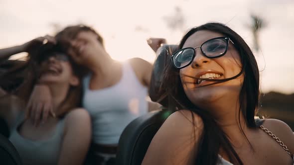 Slow motion shot of young women having fun in cabriolet at sunset