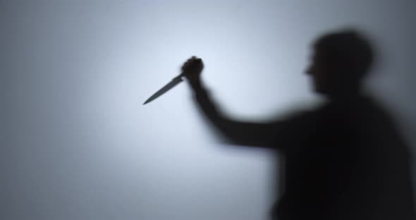 Blurred Silhouette of a Man Preparing To Stab with a Knife alt