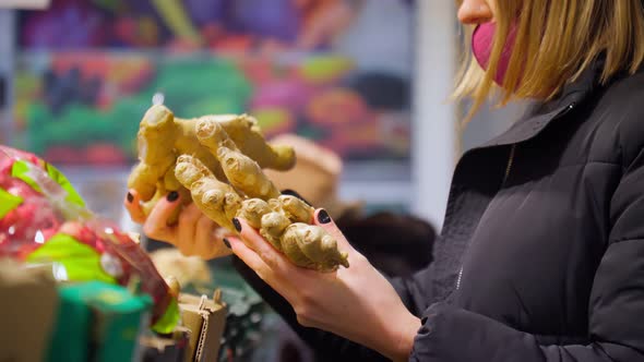 Woman in Mask Choice an Ginger in Her Hand in a Supermarket alt