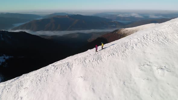 Silhouette of Two Hikers Descending a Mountain Ridge In Winter
