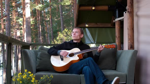 Young Man Playing Guitar Outside Glamping Tent alt