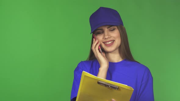 Beautiful Delivery Woman Talking on the Phone Holding a Clipboard alt