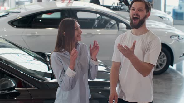 The Concept of Buying or Renting a Car. Young Happy Interracial Couple with New Car Keys. alt