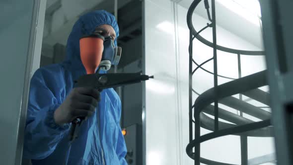 Paint shop worker spraying powder paint with an airbrush in slow motion