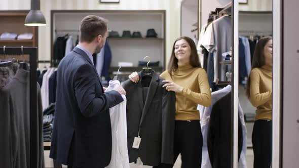 A Side View Panoramic Shot of a Young Clothing Shop Consultant Helping a Male Buyer Create a New