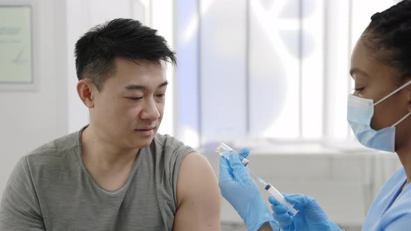 Close Up of Asian Man Watching How Medical Nurse in Protective Mask and Safety Gloves Filling alt