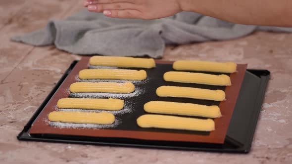 Sprinkle Raw Dough for Eclairs on a Baking Sheet with Powdered Sugar