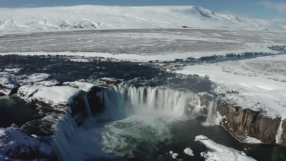 Aerial View of Godafoss Waterfall with Snowy Shore and Ice. Iceland
