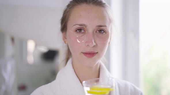 Portrait of Young Confident Beautiful Woman Drinking Refreshing Organic Detox Lemon Water in Slow alt