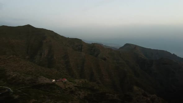 Aerial Flight Over Serpentine Road Beyound Mountains Covered with Green Forest alt