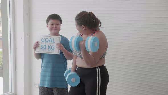 Asian family with mother in sportswear lifting dumbbell and son cheer with goal for diet. alt