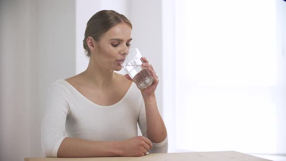 Woman Drinking Water From Glass And Looking At Camera alt