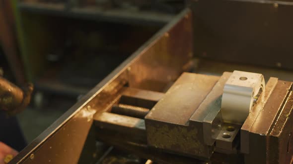 Caucasian male hands factory worker at a factory standing at a workbench and using a hummer alt
