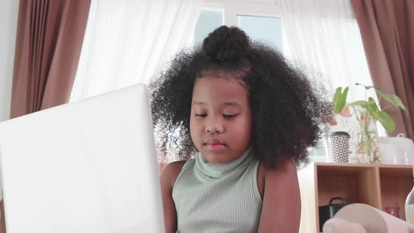Close up of African American girl searching and study by by laptop, at table in kitchen